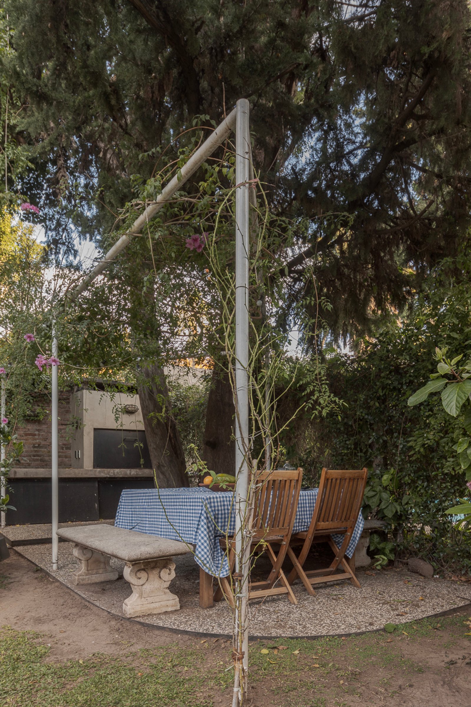 comedor exterior rústico bajo pérgola y árboles — proyecto Jardines Catamarca, por Estudio YME, en B1636 Olivos